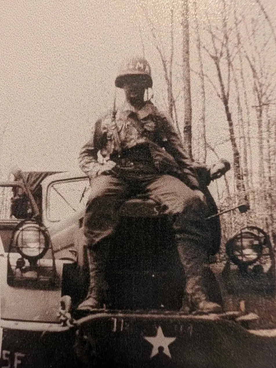 Everett Schafer assis sur un véhicule, son casque portant le prénom « Elma », celui de sa femme